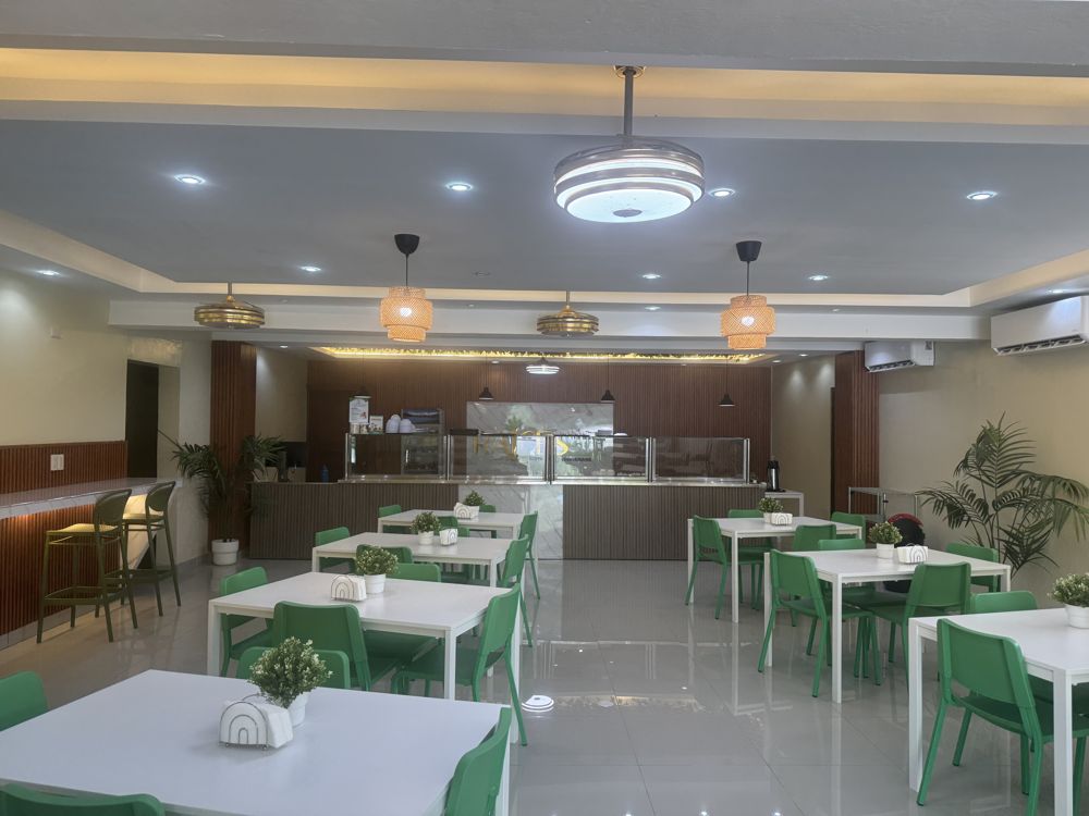 Comedor de Raíces Sur con mesas blancas y sillas verdes